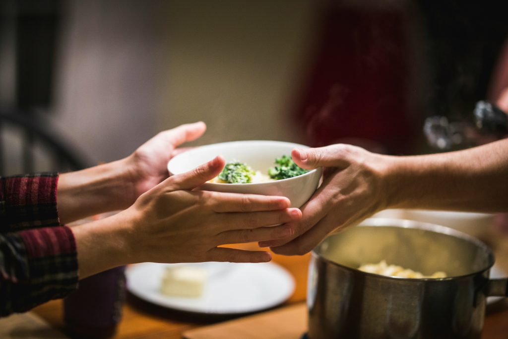 Tazón de verduras tomado por dos personas, fondo neutro, cena familiar. Tendencias 2026.